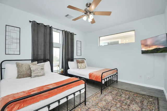 bedroom featuring a ceiling fan, visible vents, wood finished floors, and baseboards