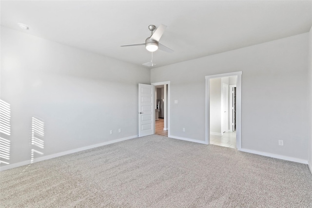 interior space with a ceiling fan, baseboards, and light colored carpet