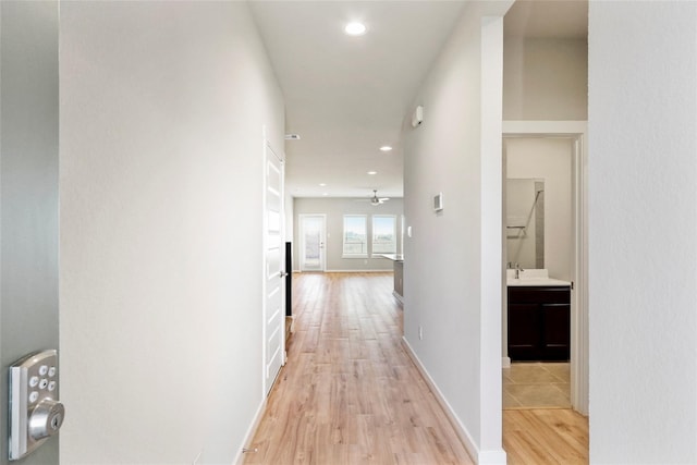 hall with baseboards, light wood-style floors, and recessed lighting