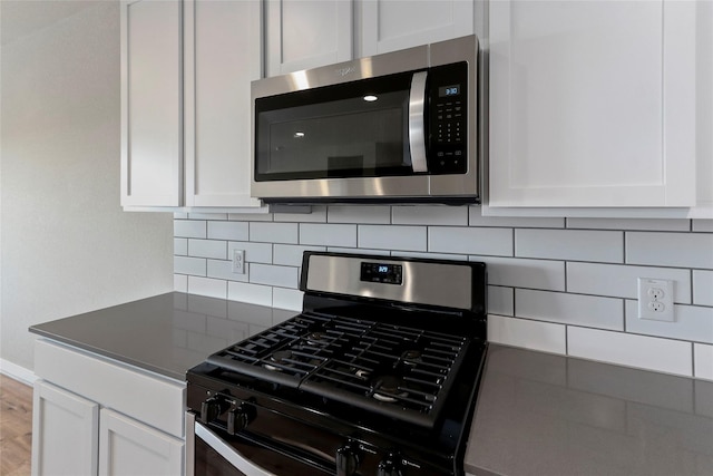 kitchen with white cabinetry, gas stove, decorative backsplash, and stainless steel microwave