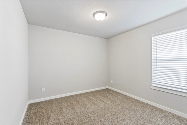 carpeted spare room featuring baseboards