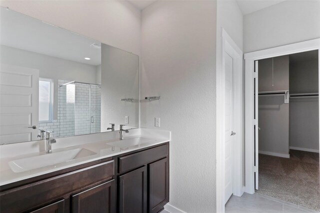 full bath with double vanity, a sink, a walk in closet, and a shower stall