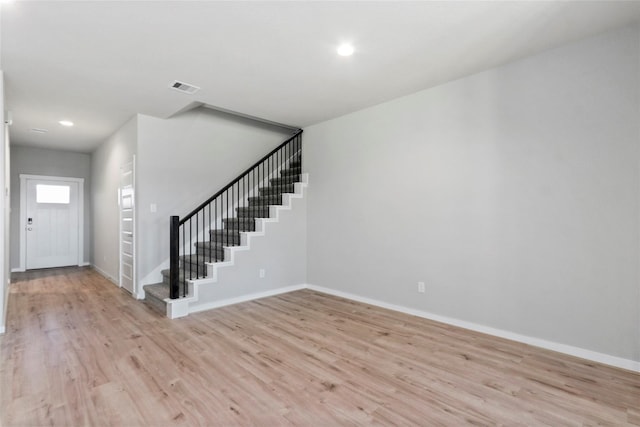 entryway with light wood-style floors, visible vents, baseboards, and stairway