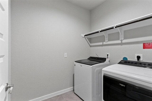 laundry room featuring light tile patterned flooring, baseboards, separate washer and dryer, and laundry area