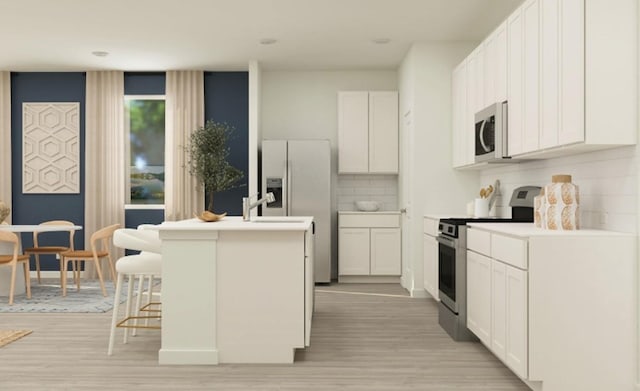 9318 Vendace Dr, Baytown, TX 77521 - kitchen featuring appliances with stainless steel finishes, a kitchen island with sink, light wood finished floors, white cabinetry, and a breakfast bar