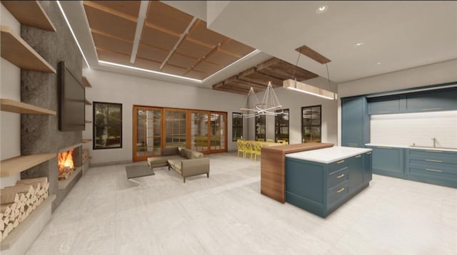 25137 Little John Cir, Hockley, TX 77447 - kitchen with blue cabinetry, a warm lit fireplace, light countertops, pendant lighting, and a chandelier