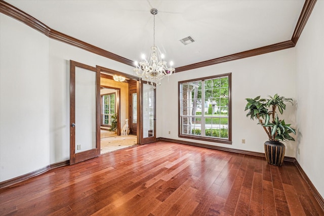 empty room with ornamental molding, a healthy amount of sunlight, hardwood / wood-style flooring, and a notable chandelier