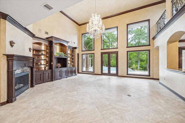 unfurnished living room with a high ceiling, a fireplace, a notable chandelier, crown molding, and visible vents