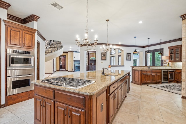 kitchen with wine cooler, stainless steel gas stovetop, visible vents, and brown cabinetry