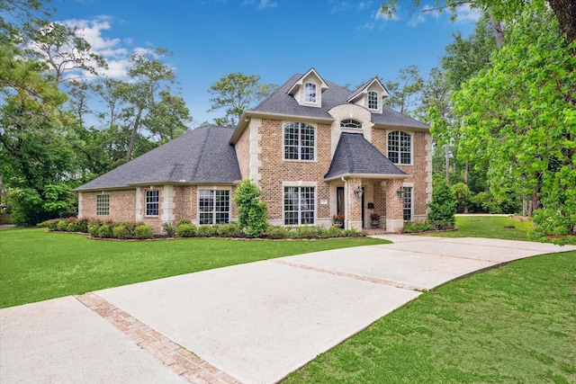 view of front of property with a front lawn, a shingled roof, and brick siding