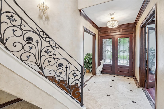 entrance foyer with crown molding, visible vents, baseboards, an inviting chandelier, and french doors