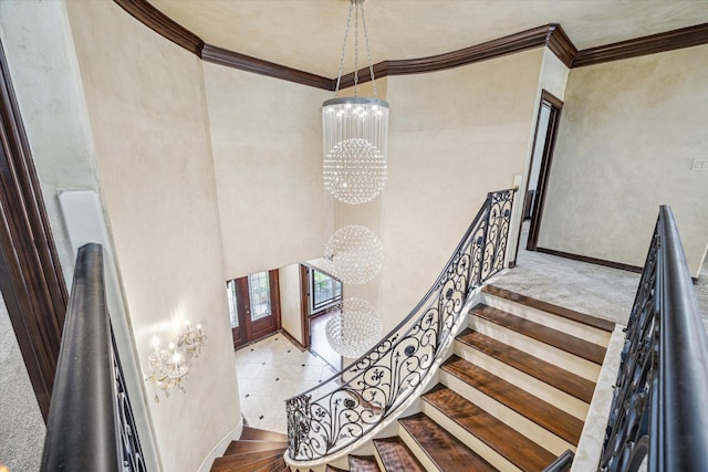stairway featuring an inviting chandelier, a towering ceiling, crown molding, and baseboards