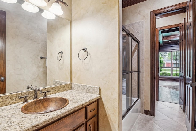 bathroom featuring tile patterned floors, a textured wall, vanity, and shower / bath combination with glass door