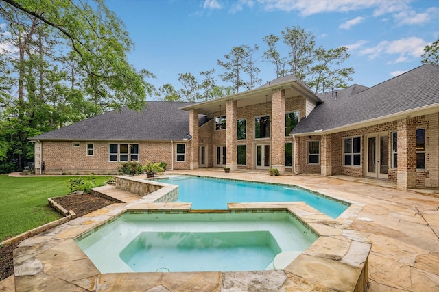 pool with a patio, a yard, french doors, and an in ground hot tub
