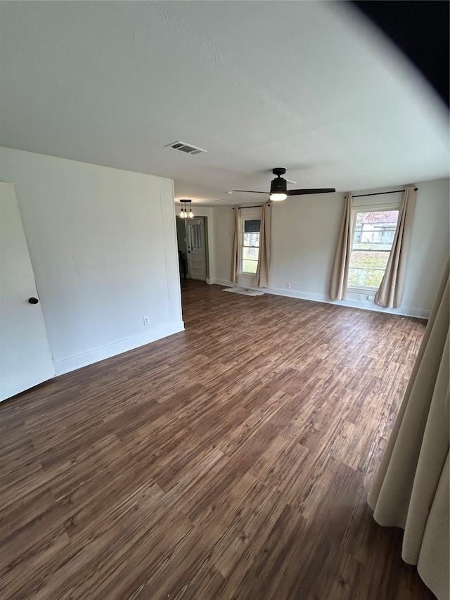 304 Tanner Ave, Cleveland, TX 77327 - unfurnished living room with dark wood finished floors, healthy amount of natural light, a ceiling fan, and baseboards
