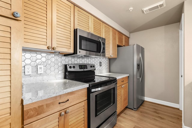 12800 Melville Dr Unit B307, Montgomery, TX 77356 - kitchen with appliances with stainless steel finishes, decorative backsplash, light wood finished floors, light brown cabinetry, and light stone countertops