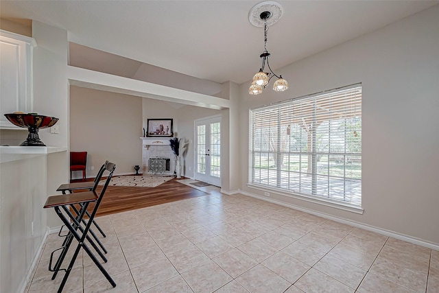 interior space featuring baseboards, a fireplace, and light tile patterned floors