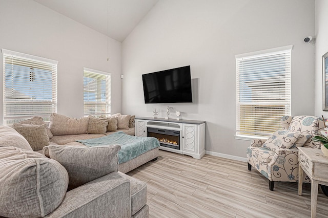 408 Long Beach Bay Dr, Katy, TX 77493 - living room with high vaulted ceiling, light wood-style flooring, and a warm lit fireplace