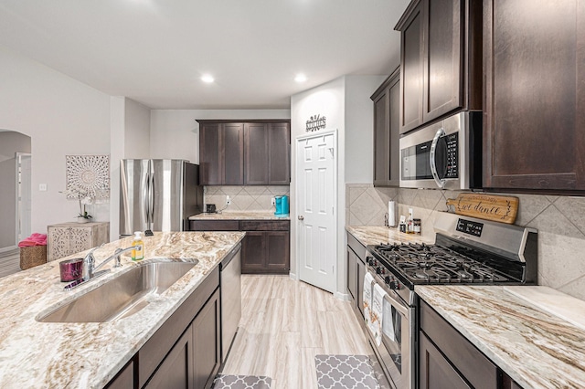 408 Long Beach Bay Dr, Katy, TX 77493 - kitchen with stainless steel appliances, dark brown cabinets, light stone countertops, arched walkways, and tasteful backsplash