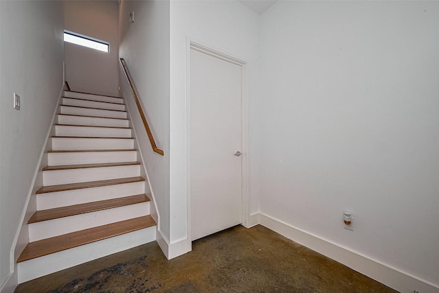 stairs featuring baseboards and concrete flooring