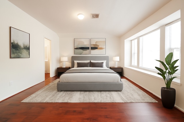 bedroom with lofted ceiling, baseboards, visible vents, and wood finished floors