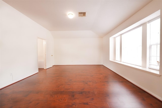 empty room featuring vaulted ceiling, visible vents, a healthy amount of sunlight, and wood finished floors