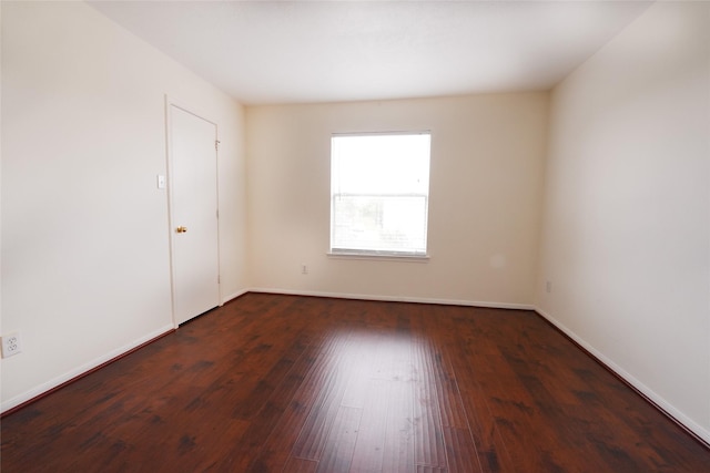 empty room with dark wood finished floors and baseboards