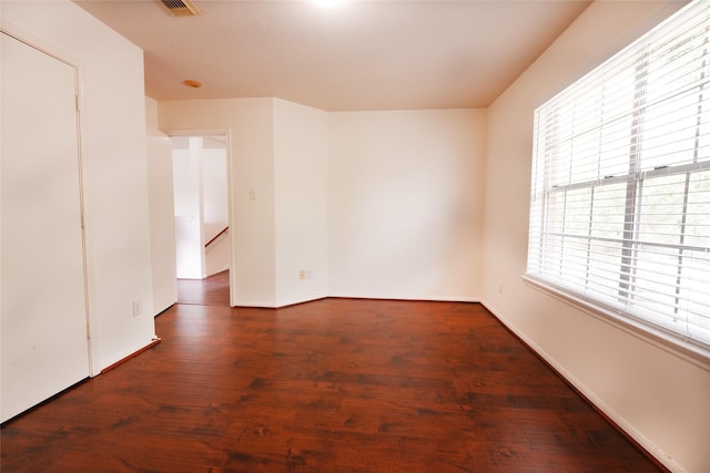 unfurnished room featuring baseboards, visible vents, and wood finished floors