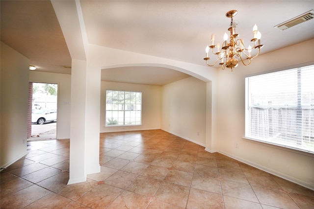 spare room with baseboards, light tile patterned floors, visible vents, a chandelier, and arched walkways