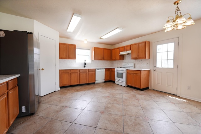 kitchen featuring under cabinet range hood, light tile patterned floors, white appliances, an inviting chandelier, and light countertops