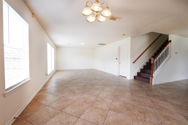 unfurnished living room with a chandelier, visible vents, light tile patterned flooring, and stairs