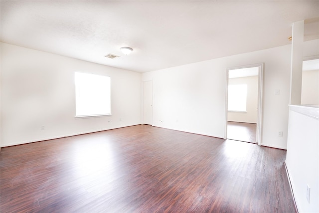 unfurnished room featuring baseboards, visible vents, and wood finished floors