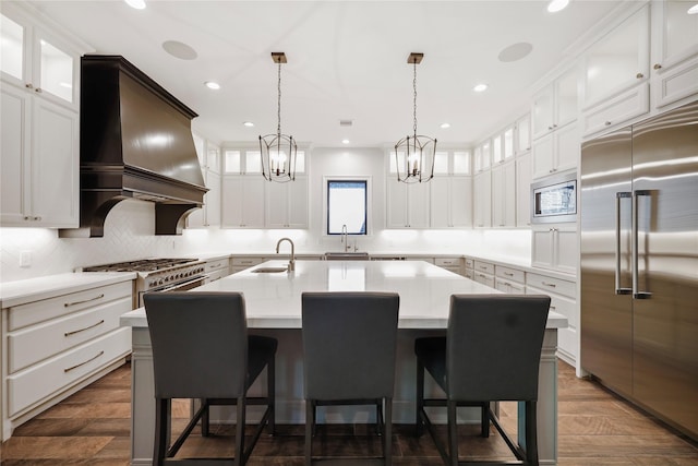 27415 Siandra Creek Ln, Spring, TX 77386 - kitchen with built in appliances, custom exhaust hood, a sink, a center island with sink, and decorative backsplash