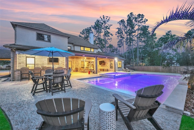 27415 Siandra Creek Ln, Spring, TX 77386 - pool at dusk featuring a fenced backyard, a patio area, a pool with connected hot tub, and an exterior structure