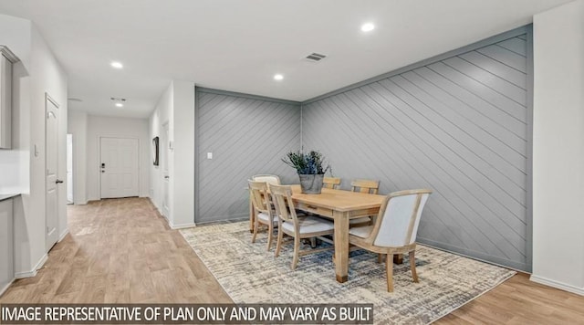 dining room with light wood finished floors, recessed lighting, visible vents, wood walls, and baseboards