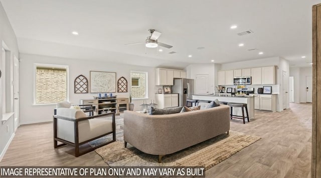 living room with light wood-type flooring, a ceiling fan, recessed lighting, and baseboards