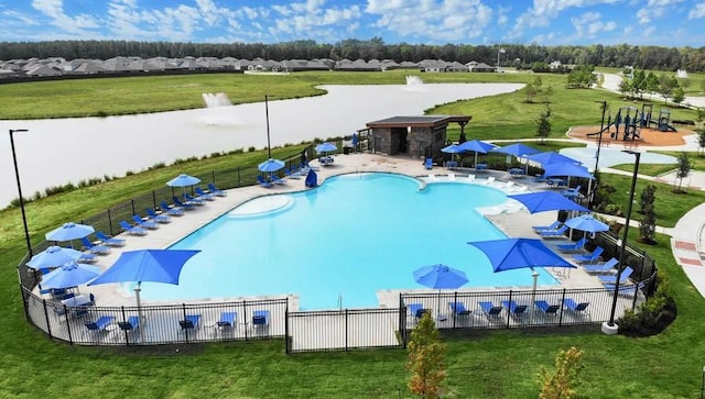 pool with a yard, a water view, and fence
