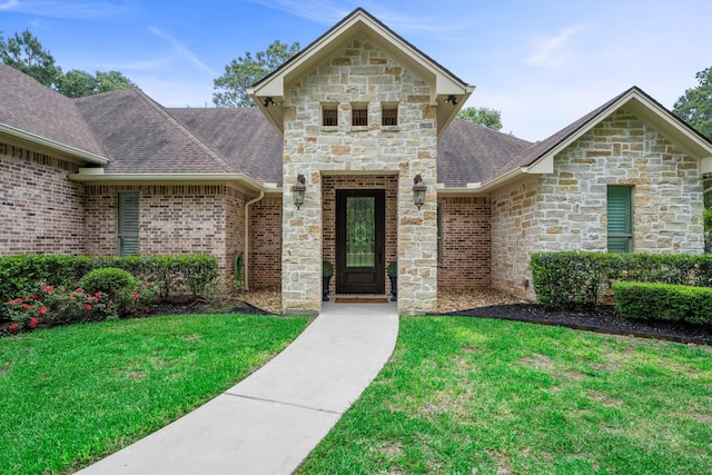 13130 Victoria Trce, Montgomery, TX 77316 - view of front of home featuring stone siding, a shingled roof, and a front yard