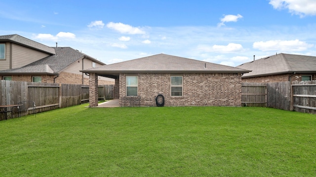 back of house featuring a yard, a fenced backyard, and brick siding