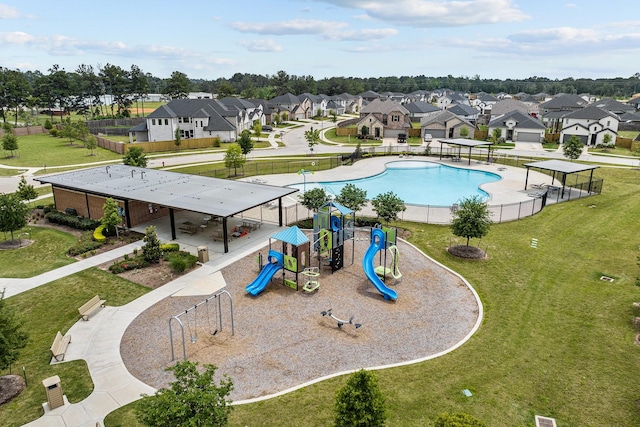 view of pool with playground community, fence, a yard, a water slide, and a residential view