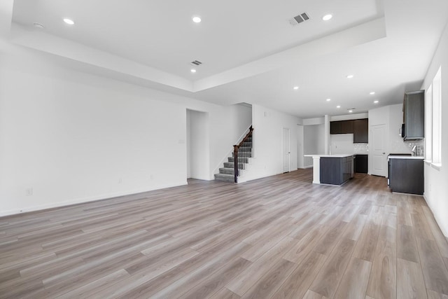 unfurnished living room featuring light wood-style floors, visible vents, recessed lighting, and stairs