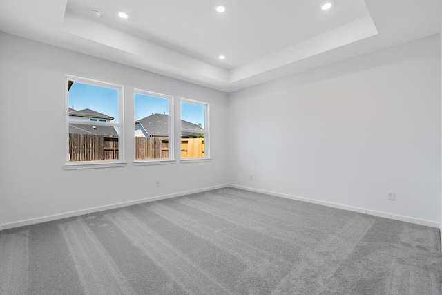 unfurnished room featuring recessed lighting, a raised ceiling, carpet, and baseboards