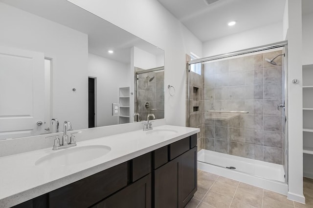 bathroom with a shower stall, tile patterned flooring, a sink, and double vanity