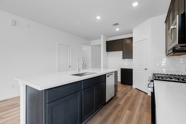kitchen with visible vents, light wood finished floors, stainless steel appliances, and a sink