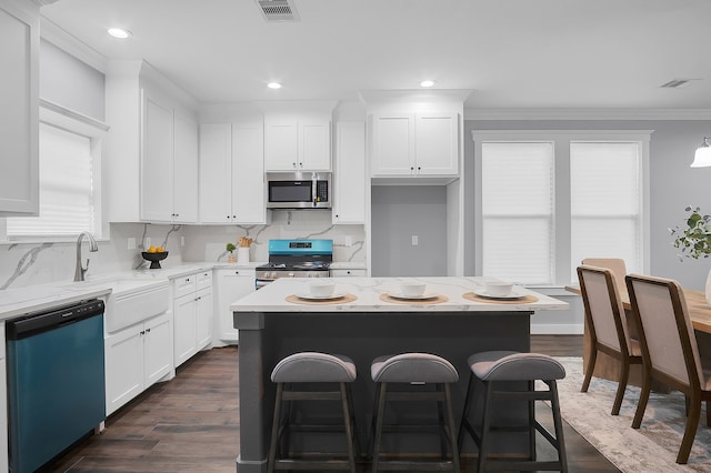 kitchen featuring visible vents, decorative backsplash, a kitchen bar, and stainless steel appliances