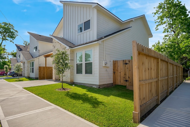 view of home's exterior featuring board and batten siding, fence, a yard, and driveway