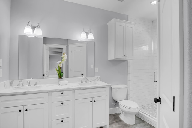 full bathroom with double vanity, toilet, a sink, and a stall shower