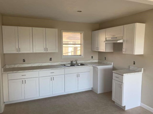 kitchen with white cabinets, under cabinet range hood, light countertops, and a sink