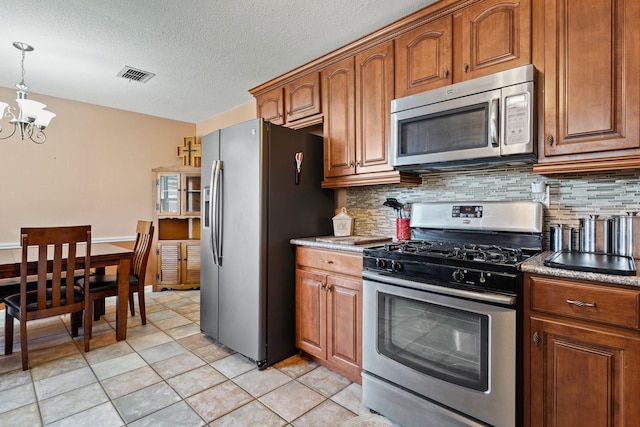 kitchen with stainless steel appliances, brown cabinets, backsplash, and a chandelier