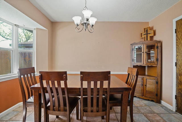 dining room with baseboards, a chandelier, and stone finish flooring